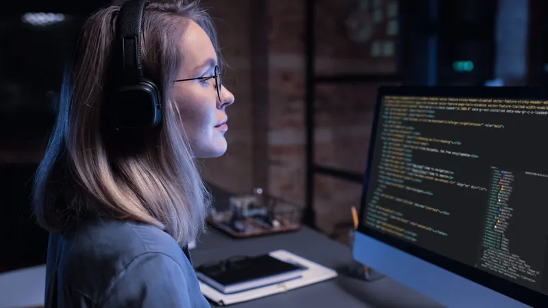 Professional working at a screen of code in cool blue light.